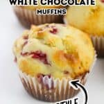 A raspberry white chocolate muffin in a paper liner sits on a white surface, labeled as "Bakery Style Raspberry White Chocolate Muffins"—a perfect treat for fans of delicious Raspberry White Chocolate Muffins.