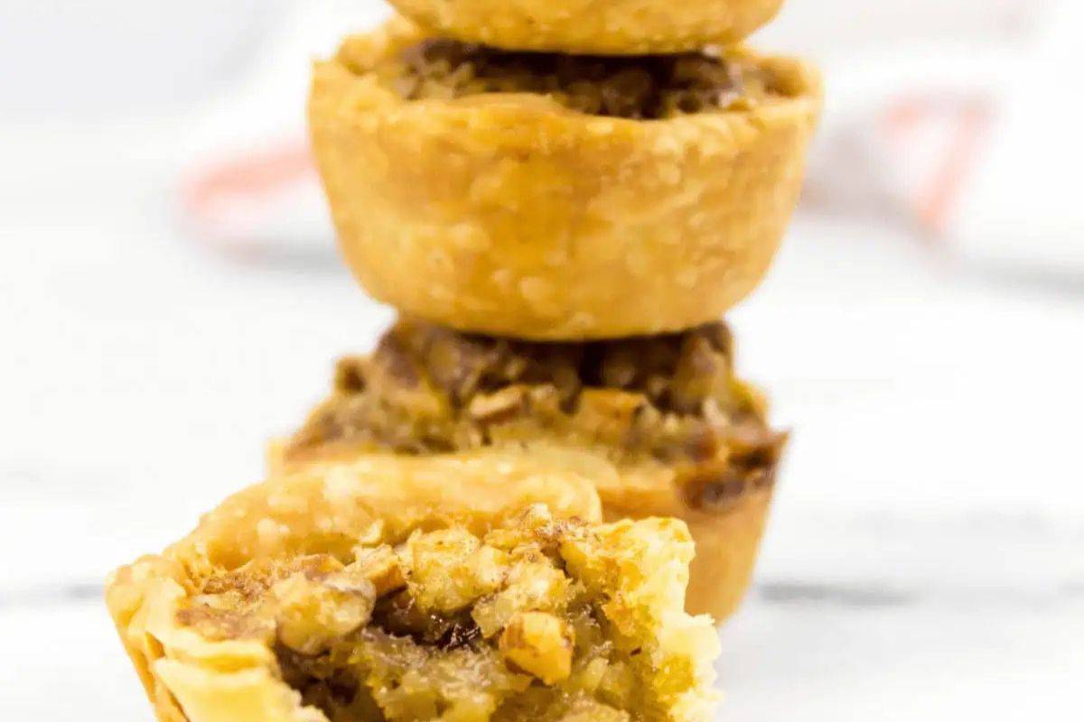 A close-up of a pecan pie with a glossy, caramelized surface and a dense layer of pecans on top of a flaky crust.