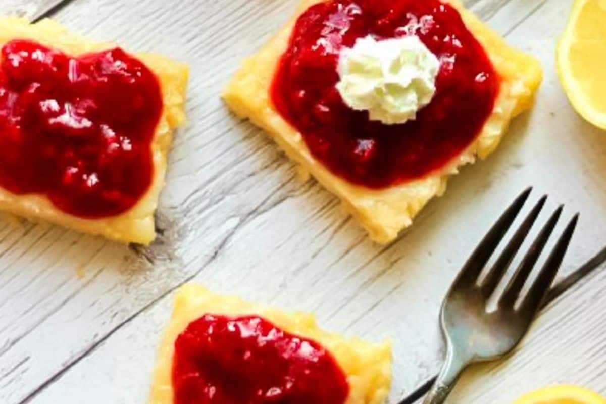 A chilled glass of raspberry lemonade with visible raspberries and lemon slices, served over ice with a straw.