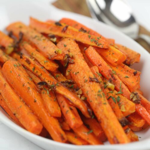 Oven Roasted Baby Carrots with Garlic in a white serving dish.