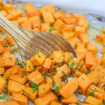 A spoon in the Savory Roasted Sweet Potatoes with Rosemary.