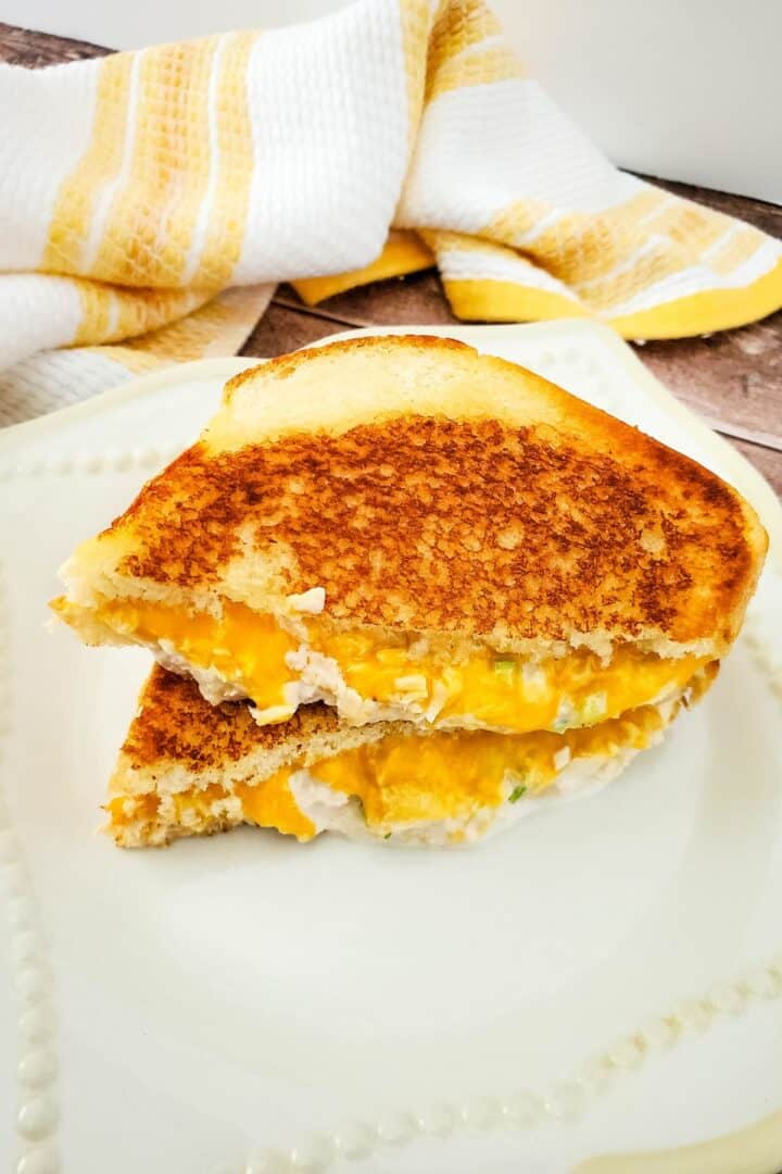 An air fryer tuna melt sandwich cut in half on a white plate.