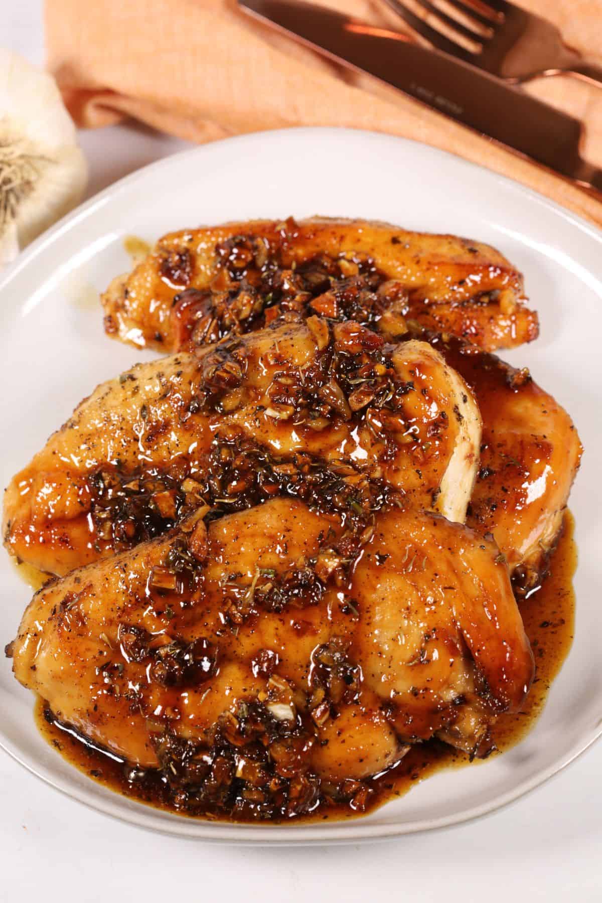 Three pieces  covered in a dark, seasoned sauce reminiscent of Baked utensils and a garlic bulb in the background.