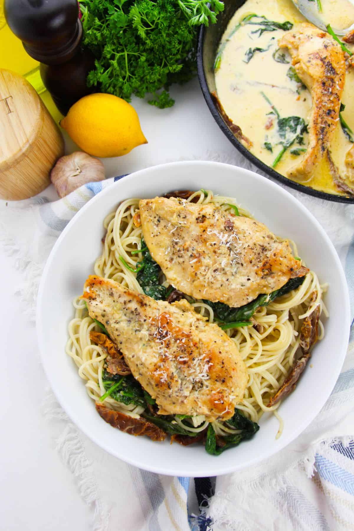 A bowl of Chicken cutlets.lemon, and herbs in the background.