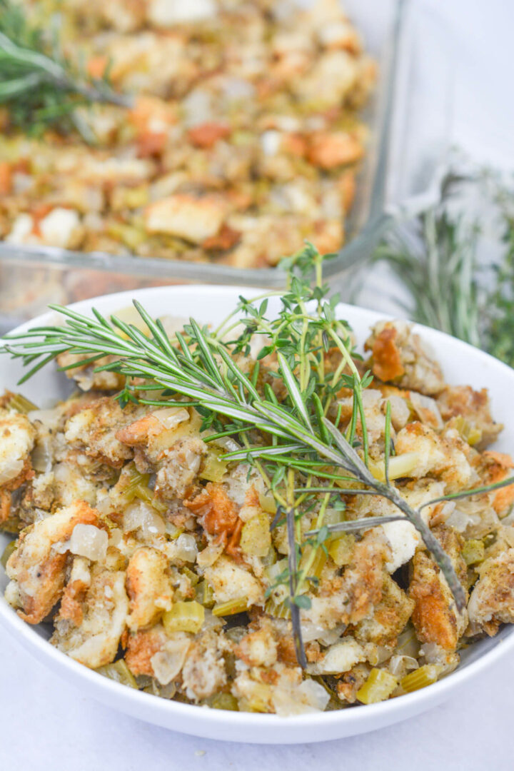 Sage and onion stuffing recipe in a bowl with fresh herbs on top. 