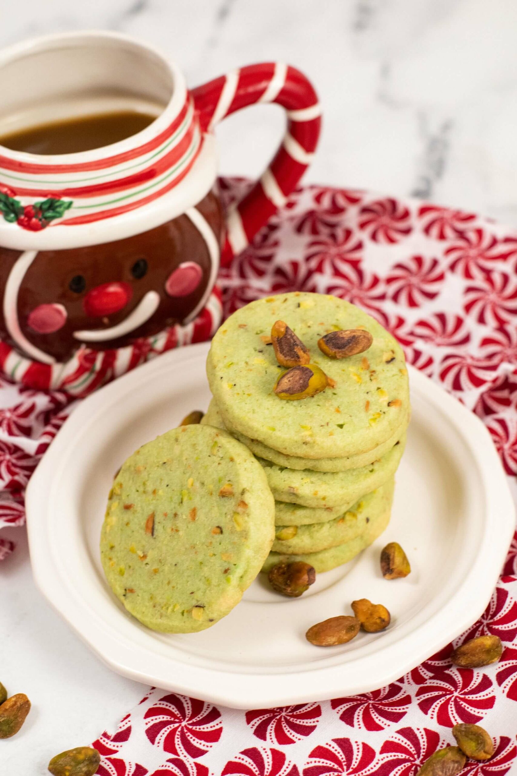 Pistachio Cookies surrounded by the nuts on a white plate.