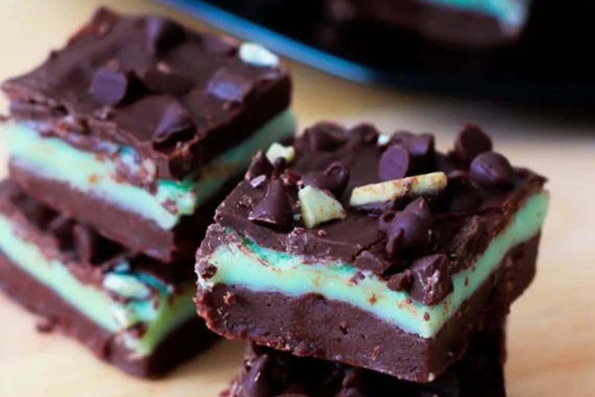 Three stacked pieces of Andes mint chocolate chip fudge, layered with a green mint center and topped with chocolate chips and mint pieces.