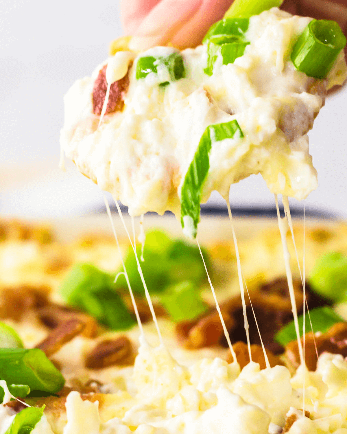 A person enjoying a delicious cracker with melted cheese and fresh greens.