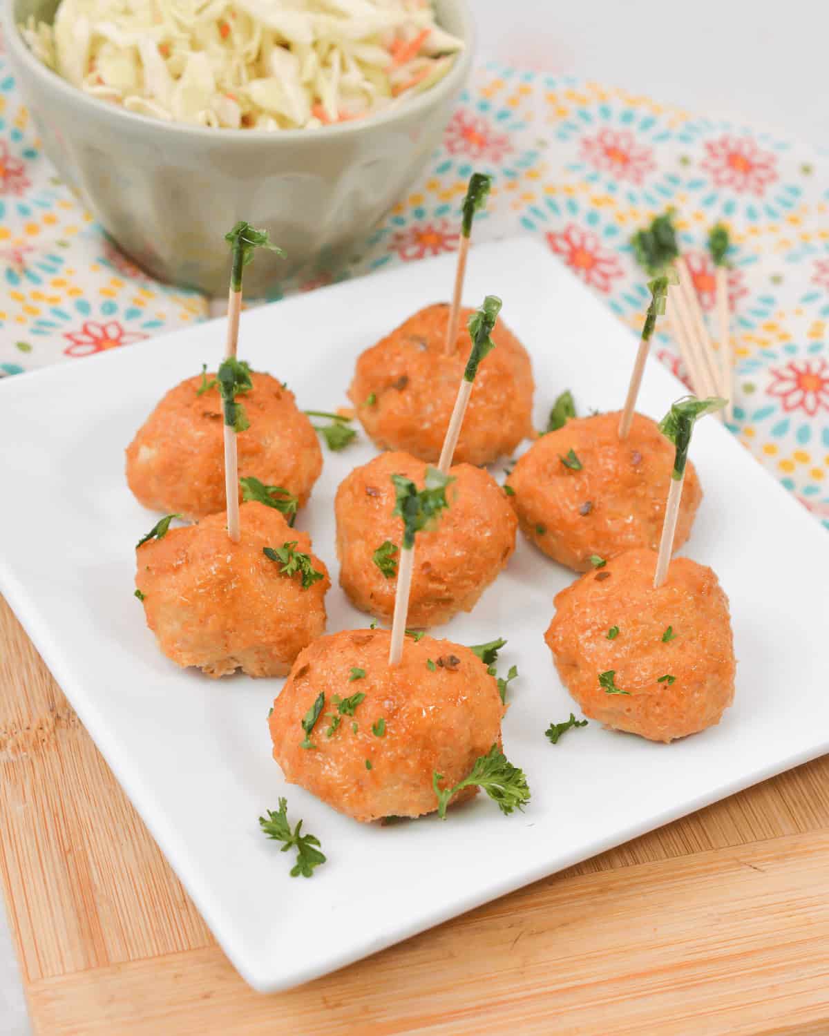 Firecracker meatballs on a white plate with a side of coleslaw.
