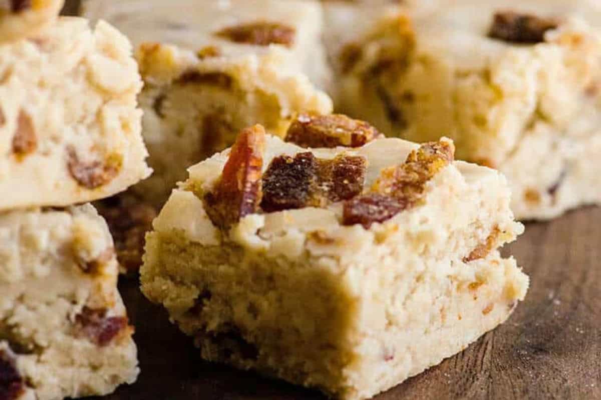 Close-up of several square pieces of maple bacon fudge displayed on a wooden surface.