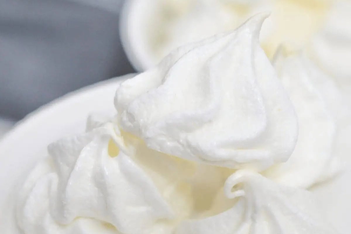 Close-up of a swirl of white meringue cookies on a white dish, reminiscent of traditional Russian Christmas food, with a soft, fluffy texture and a blurred background.