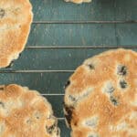 Four toasted Welsh cookies with raisins are cooling on a wire rack.