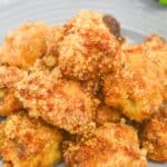 A plate of golden-brown, breaded and baked chicken nuggets served on a gray dish, with a dipping sauce and parsley in the background—perfect for pairing with savory Air Fryer Steak Bites for a delicious appetizer spread.