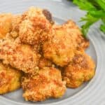 A plate of golden-brown breaded chicken nuggets sits next to a bunch of fresh parsley on a gray plate, making for a delicious pairing alongside your favorite Air Fryer Steak Bites.