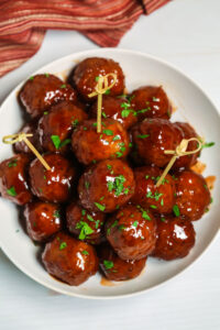 Barbecue meatballs on a plate, served with toothpicks.