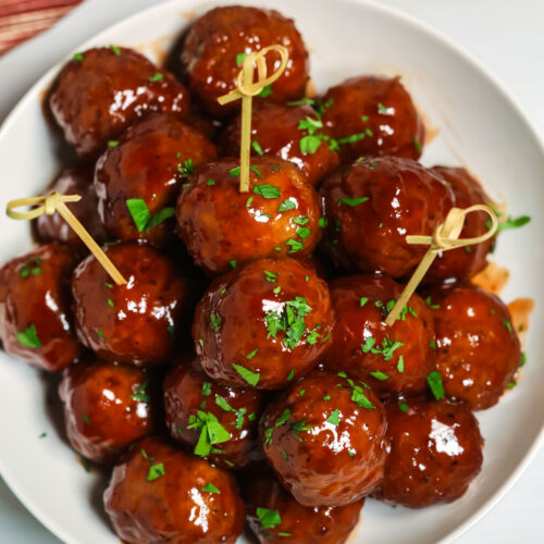 Barbecue meatballs on a plate, served with toothpicks.