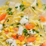 A close-up of a bowl with parsley, and chunks of meat in a clear broth.