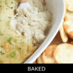 A delectable spread of Cream Cheese and Crab Dip, baked to perfection and served with a wooden spatula, nestled among appetizing round crackers.