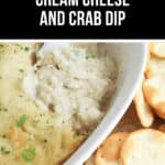 A white dish brims with a savory cream cheese and crab dip, baked to perfection and garnished with fresh herbs. Crisp crackers are thoughtfully arranged alongside for the perfect bite.