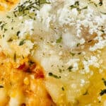 Close-up of a slice of cheese lasagna topped with grated cheese and herbs on a wooden board, exuding the same irresistible allure you'd find in a tray of meatball sliders.