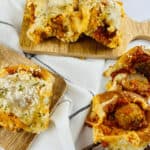 Meatball sliders nestled with sauce and cheese grace wooden boards, against a backdrop of white cloth.