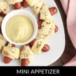 A plate of Little Smokies Pigs in a Blanket is artfully arranged around a bowl of tangy mustard.