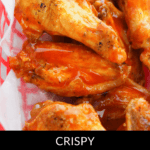 Crispy oven-baked buffalo wings, perfectly coated in tangy orange sauce, served on a white-lined basket.