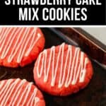 Three bright pink Strawberry Cake Mix Cookies with white icing drizzle rest on a dark baking sheet.