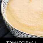 A bowl of creamy Tomato Basil Bisque served in a stylish white and black patterned bowl, with "Tomato Basil Bisque" text displayed below the image.