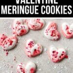 Heart-shaped pink and white Meringue Cookies adorned with red, pink, and white sprinkles rest on a light textured surface, accompanied by a banner that reads "Light Valentine Meringue Cookies.