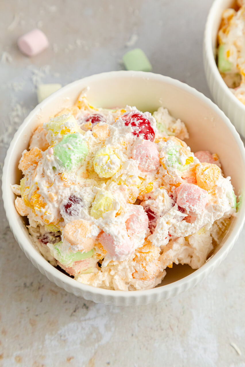 A white dish of Ambrosia Salad with Cool Whip.


