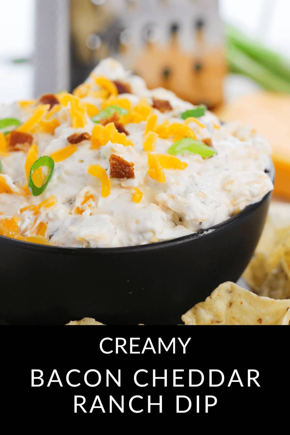 Bacon Cheddar Ranch Dip served in a bowl, crowned with crispy bacon bits and fresh green onions, accompanied by a side of crunchy chips.