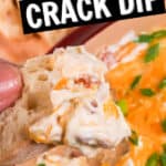 A person holding a piece of bread with cowboy crack dip, cheese, and green onions.