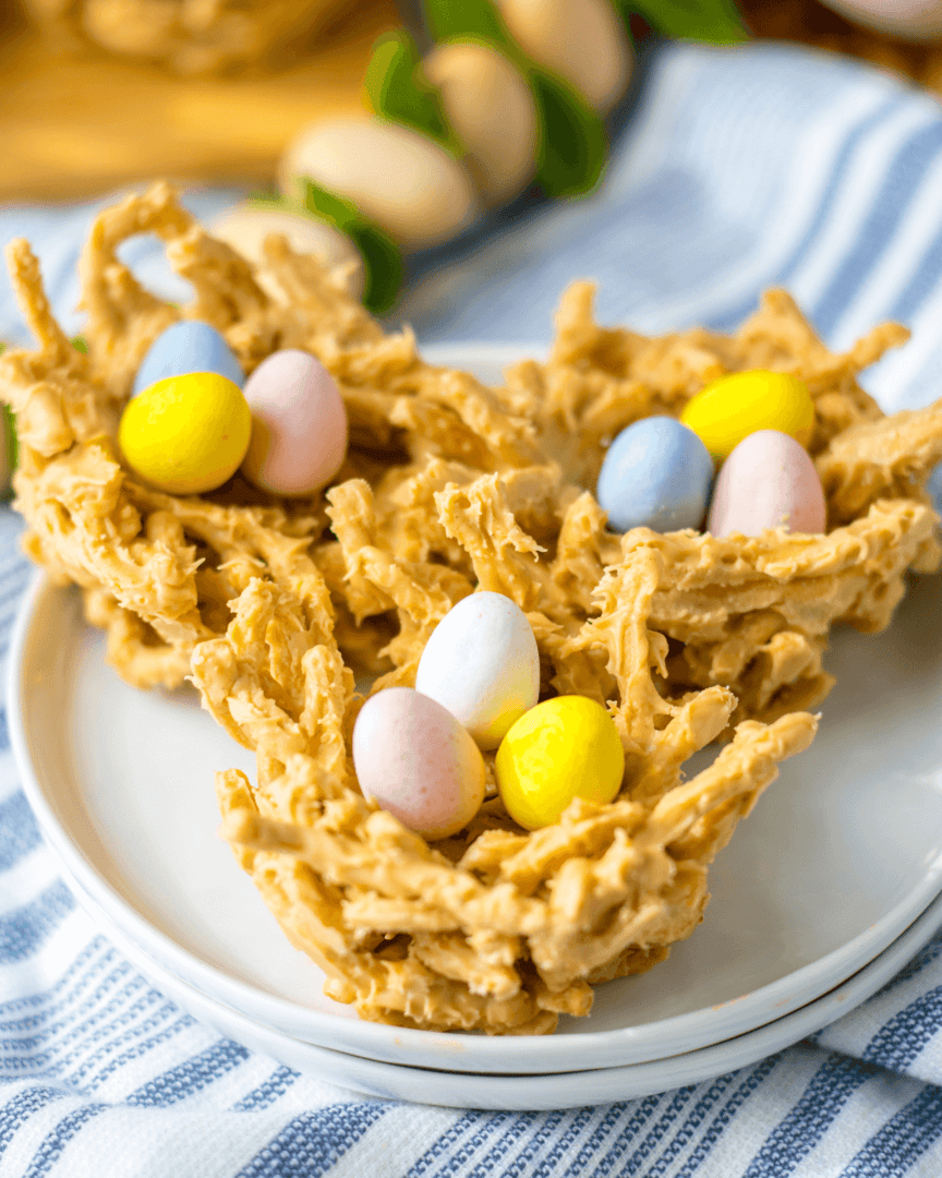 A homemade Easter-themed bird’s nest cookies with pastel-colored candy eggs on a white plate.