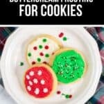 A white plate with three cookies topped with Buttercream Frosting for Cookies in red, green, and white, plus festive sprinkles, sits on a plaid cloth.