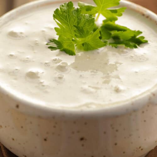 A white bowl with chunky blue cheese sauce with parsley on top.
