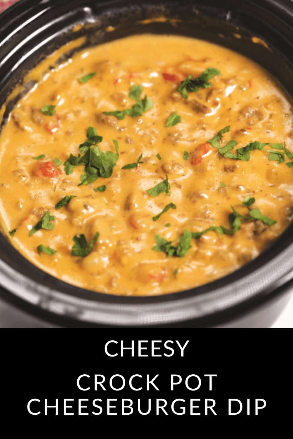 A Crock Pot filled with creamy Cheeseburger Dip, garnished with chopped herbs.