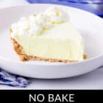 A slice of no-bake Lemonade Frozen Pie with a graham cracker crust, topped with whipped cream, served on a white plate. A larger portion of the pie is visible in the background. Text reads: "No Bake Lemonade Frozen Pie.