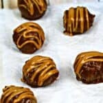 Six chocolate truffles drizzled with caramel are arranged on parchment paper, reminiscent of decadent Peanut Butter Bon Bons, with an Oreo cookie package partially visible in the background.