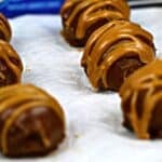 Truffles with a drizzle of peanut butter sit on parchment paper, with an Oreo cookie package partially visible in the background.