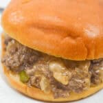 Close-up of a Philly Cheese Steak Sloppy Joe sandwich with savory beef mixture and onions, served on a white plate.