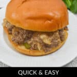A Philly cheese steak sloppy joe sits invitingly on a white plate, bursting with beef filling and melted cheese inside a bun. Text overlay reads, "Quick & Easy Philly Cheese Steak Sloppy Joes.