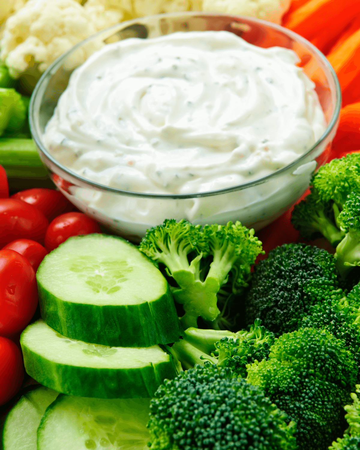 A bowl of Sour Cream Ranch Dip surrounded by vegetables.