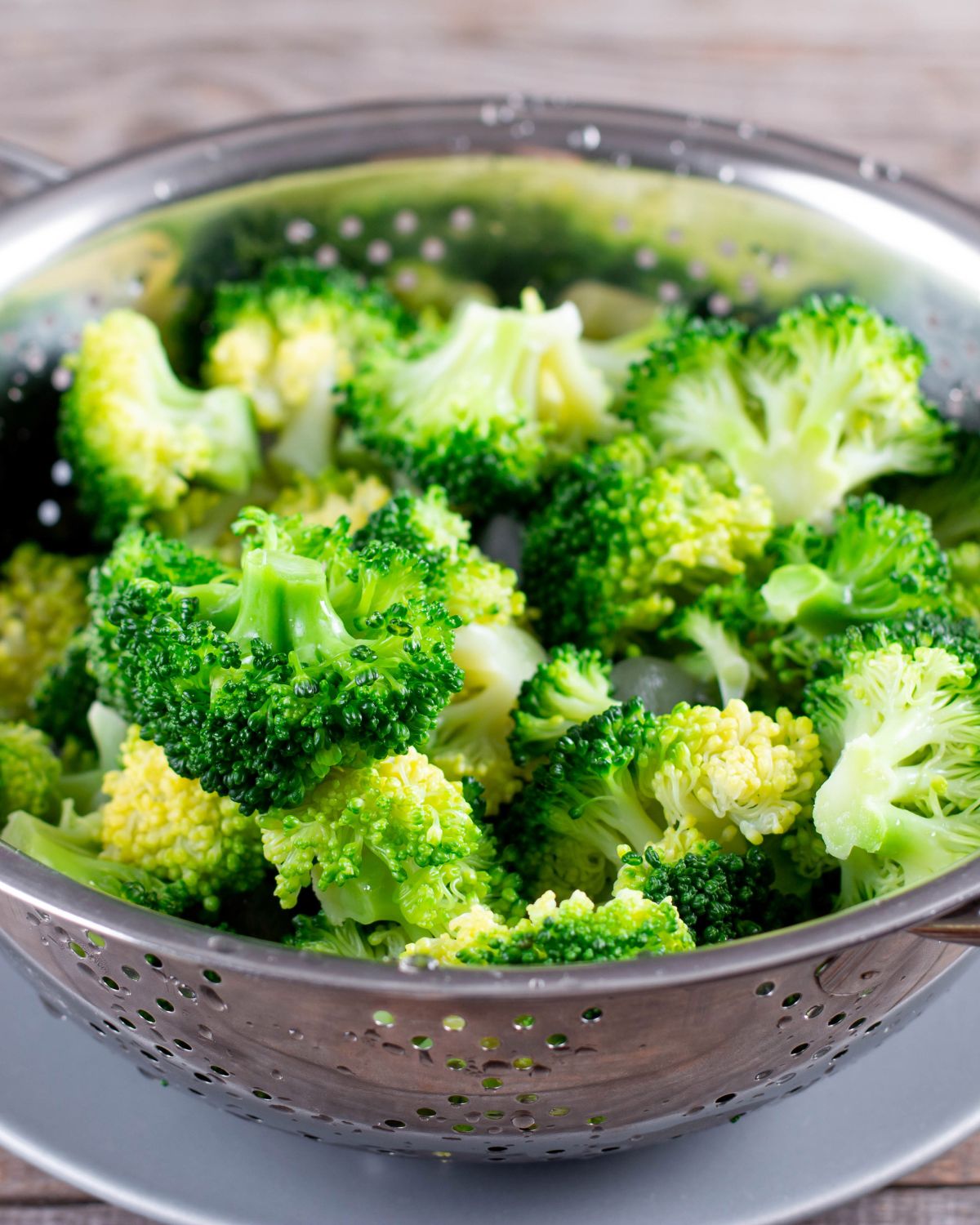 A colander full of cooked broccoli.