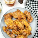 A white plate of the air fryer chicken strips with a black and white check table cloth.
