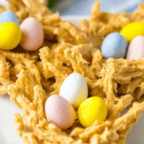 Edible nests made from crunchy noodles coated in a caramel-colored substance, featuring pastel-colored chocolate eggs, make delightful Easter treats for kids.