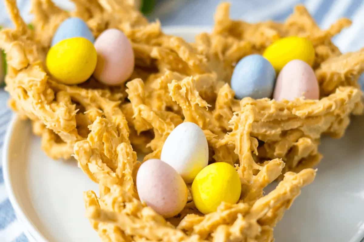 Edible nests coated in a caramel-colored substance, featuring pastel-colored chocolate eggs, make delightful Easter treats for kids.