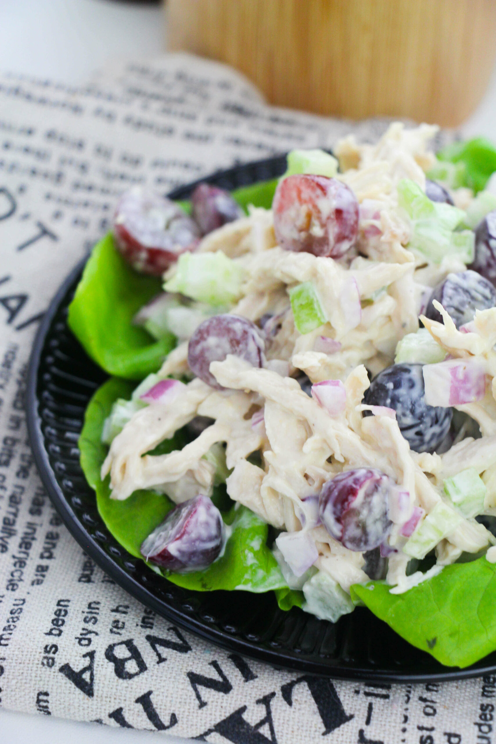 A side view of the chicken salad with grapes and almonds on a bed of greens.
