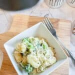 The meal on a check placemat with a bowl of the pasta and a fork.