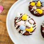 A dessert topped with pastel-colored candies and white icing on a white plate.